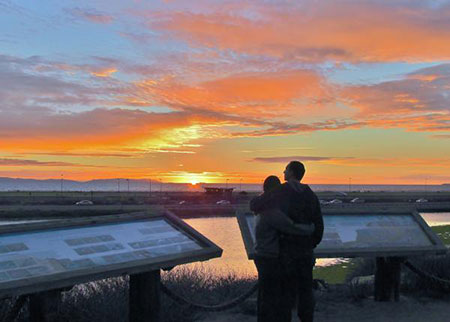 photo of a couple in front of signage and a sunset